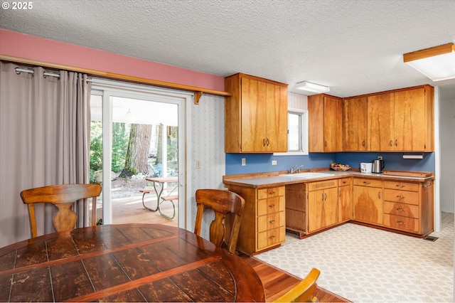 kitchen with brown cabinetry, a sink, and a textured ceiling