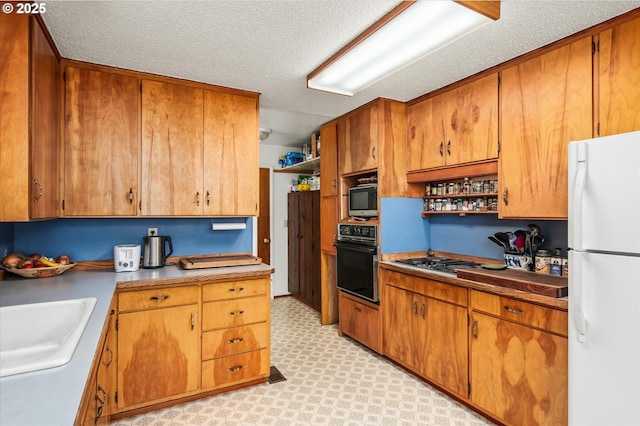 kitchen with light floors, oven, a sink, freestanding refrigerator, and open shelves