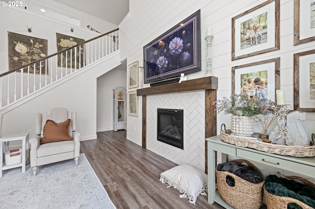 living room with hardwood / wood-style flooring, a tile fireplace, and a high ceiling