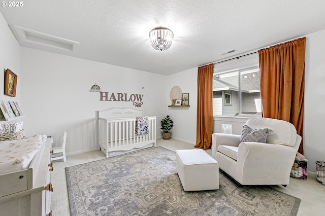 bedroom featuring carpet floors, a crib, and a textured ceiling