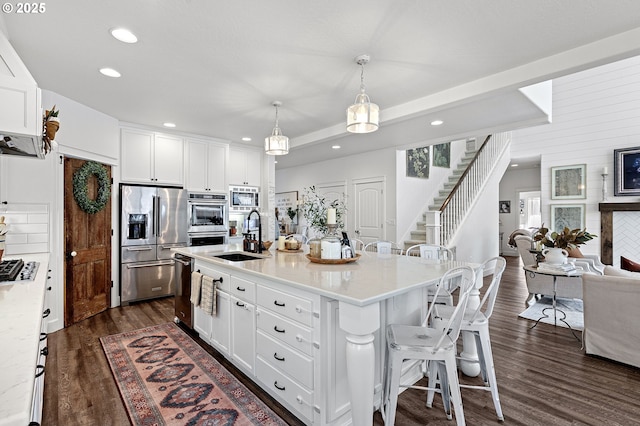 kitchen featuring sink, stainless steel appliances, an island with sink, and white cabinets