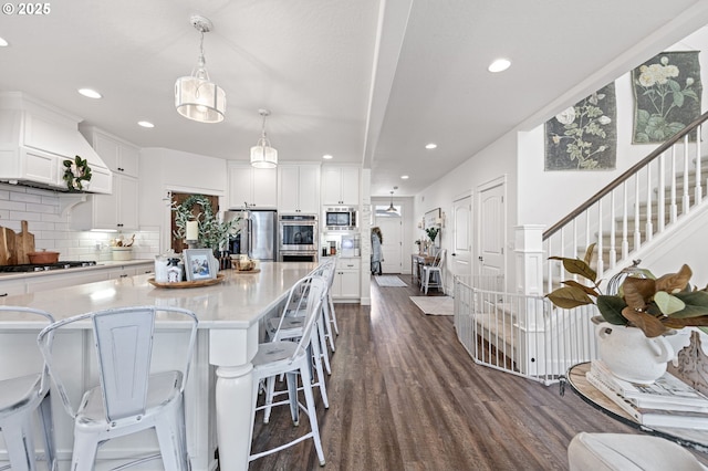 kitchen featuring pendant lighting, appliances with stainless steel finishes, white cabinetry, a center island, and tasteful backsplash