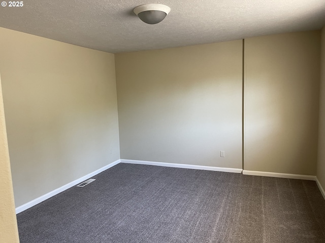 spare room with a textured ceiling and dark carpet