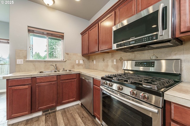 kitchen featuring visible vents, a sink, tasteful backsplash, appliances with stainless steel finishes, and brown cabinetry