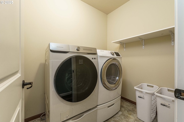 washroom with baseboards, laundry area, and washing machine and clothes dryer