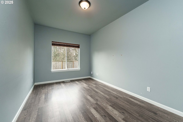 empty room featuring baseboards and dark wood-style flooring