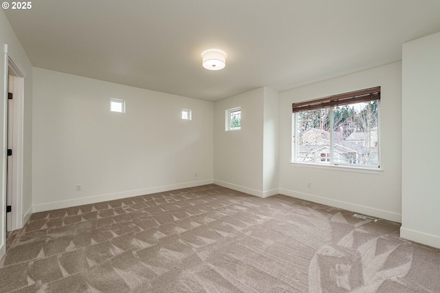 unfurnished room featuring visible vents, plenty of natural light, carpet, and baseboards