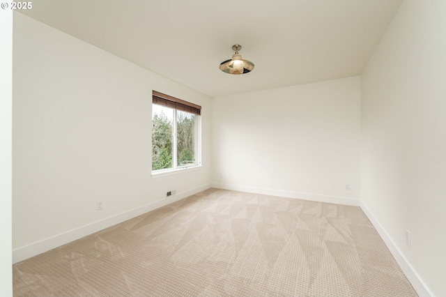 unfurnished room with light carpet and baseboards