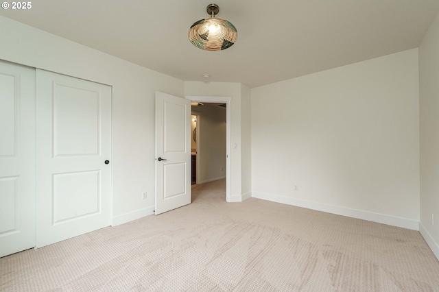 unfurnished bedroom featuring light carpet, a closet, and baseboards