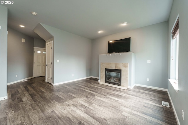 unfurnished living room with a fireplace, wood finished floors, visible vents, and baseboards