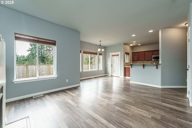 unfurnished living room with visible vents, baseboards, recessed lighting, dark wood-style floors, and a notable chandelier