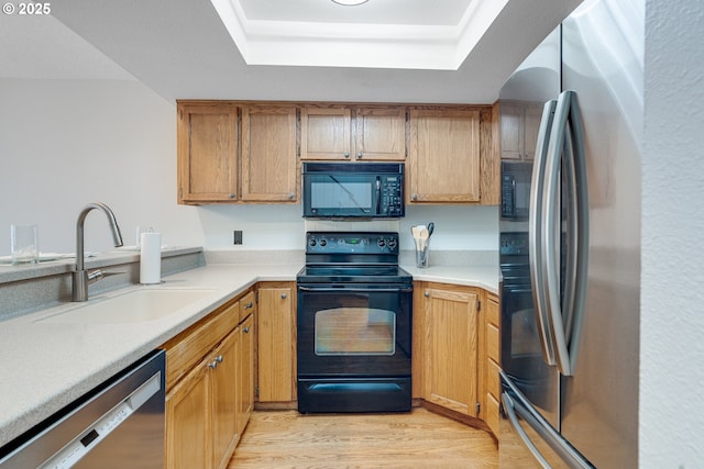 2038 Titan Ter, West Linn, OR 97068 - kitchen featuring black appliances, a tray ceiling, light countertops, and light wood-style floors