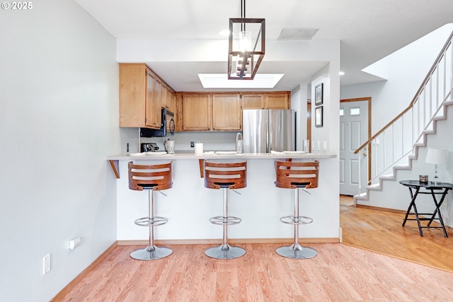 2038 Titan Ter, West Linn, OR 97068 - kitchen with freestanding refrigerator, light wood-style flooring, a kitchen breakfast bar, and light countertops