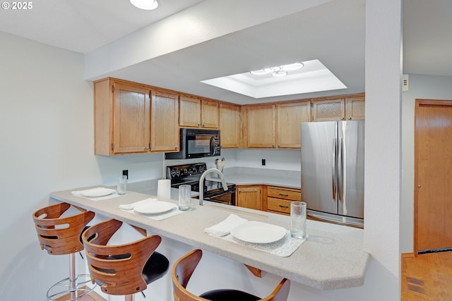 2038 Titan Ter, West Linn, OR 97068 - kitchen featuring black appliances, a peninsula, light countertops, and a kitchen bar