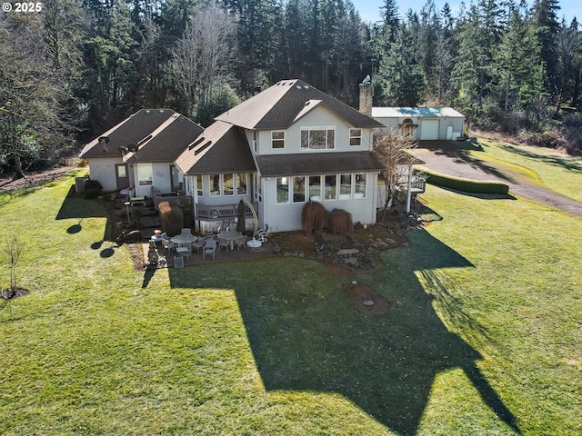 rear view of property featuring a garage, a yard, and a patio area