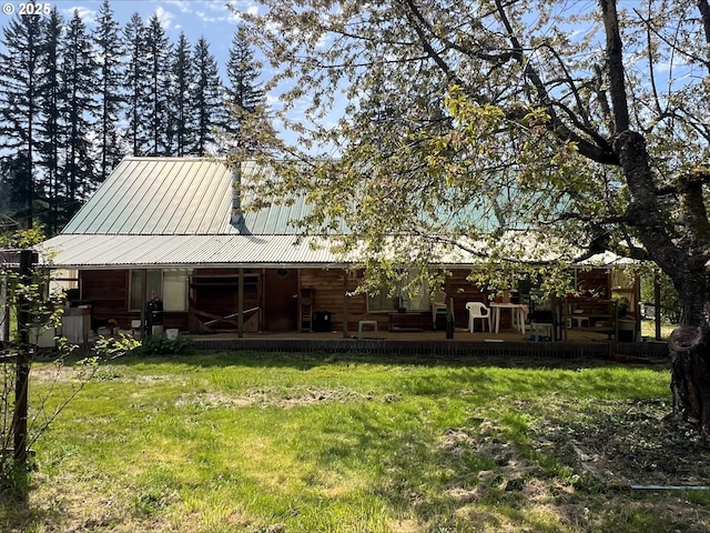 rear view of house featuring a yard, metal roof, and a porch