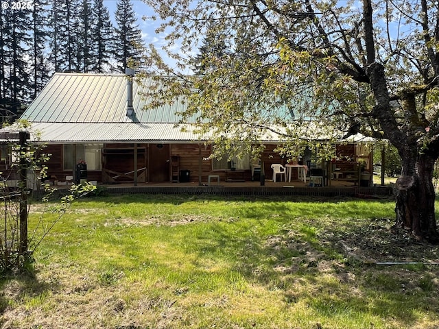 rear view of property featuring a porch, a yard, and metal roof