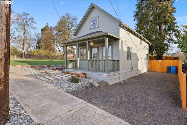 view of front facade featuring fence, covered porch, and driveway