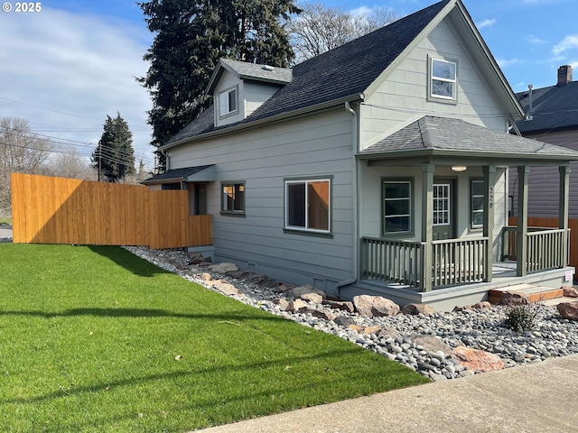 view of property exterior with a lawn, a porch, roof with shingles, and fence