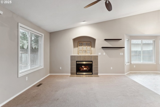 unfurnished living room with ceiling fan, a fireplace, and light carpet