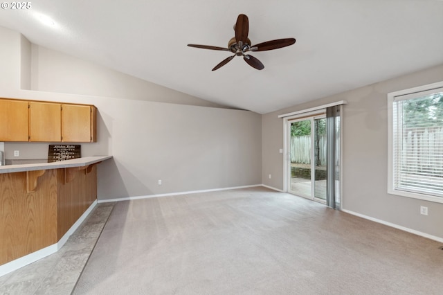 interior space with ceiling fan, light colored carpet, vaulted ceiling, and a wealth of natural light