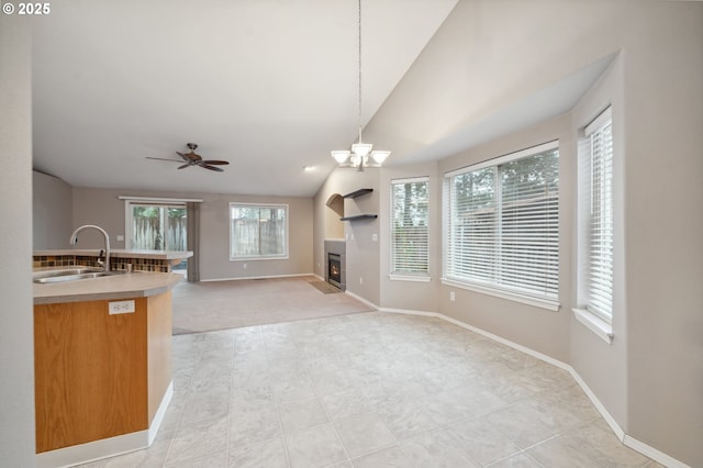 kitchen featuring ceiling fan with notable chandelier, lofted ceiling, decorative light fixtures, and sink