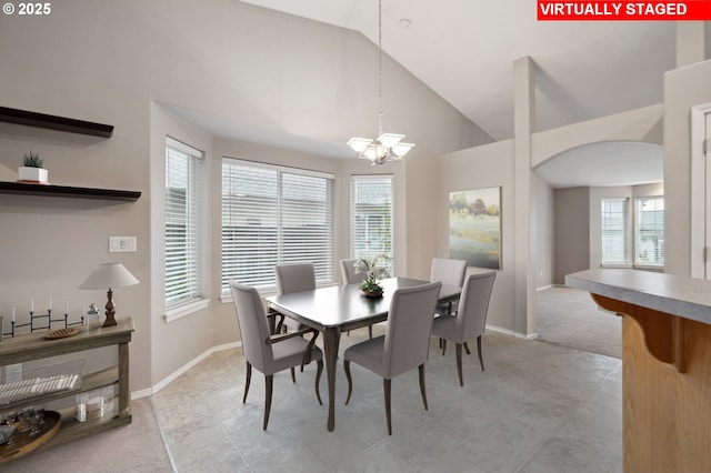 dining room with high vaulted ceiling, light carpet, and an inviting chandelier