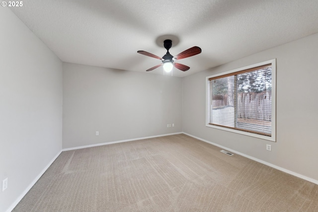 spare room featuring ceiling fan, light colored carpet, and a textured ceiling