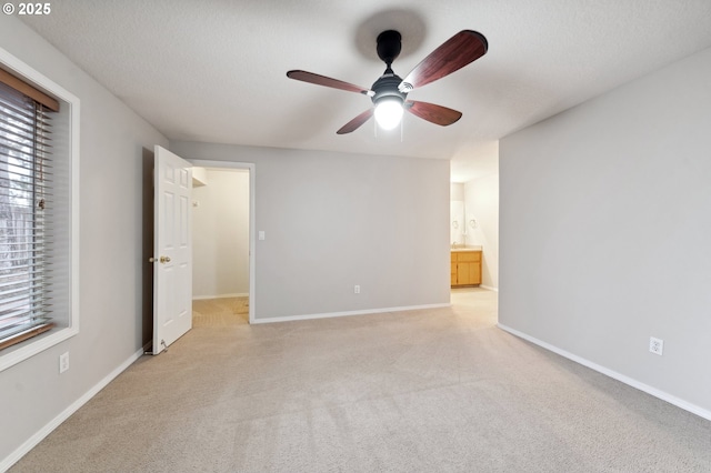 unfurnished bedroom with light carpet, ceiling fan, a textured ceiling, and ensuite bathroom