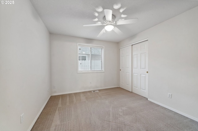 unfurnished bedroom with light colored carpet, a closet, and ceiling fan