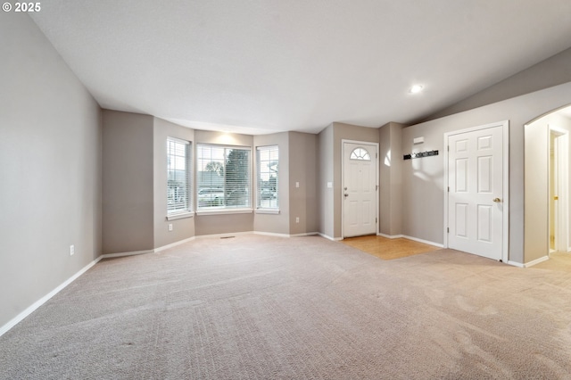 unfurnished living room with lofted ceiling and light colored carpet