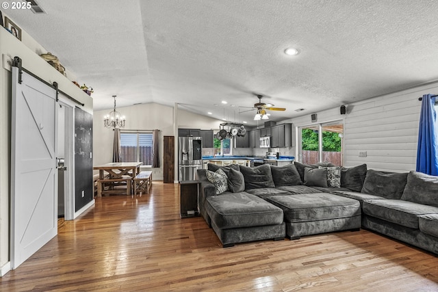 112 Stoneway Ln, Longview, WA 98632 - living room featuring a barn door, a textured ceiling, light wood-type flooring, a chandelier, and vaulted ceiling