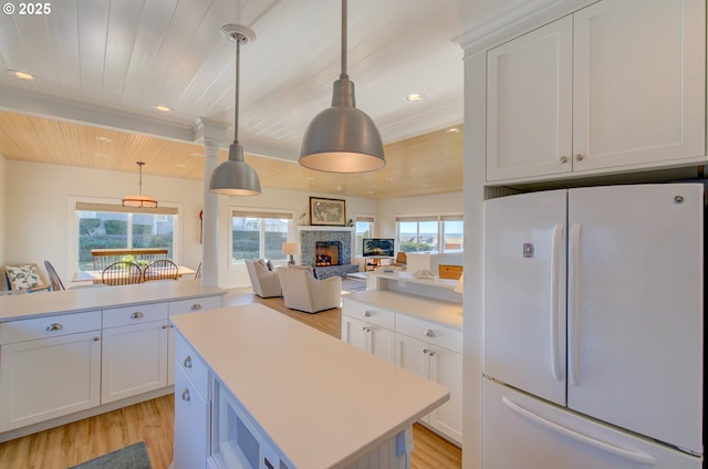 kitchen featuring hanging light fixtures, white refrigerator, white cabinets, a kitchen island, and wooden ceiling