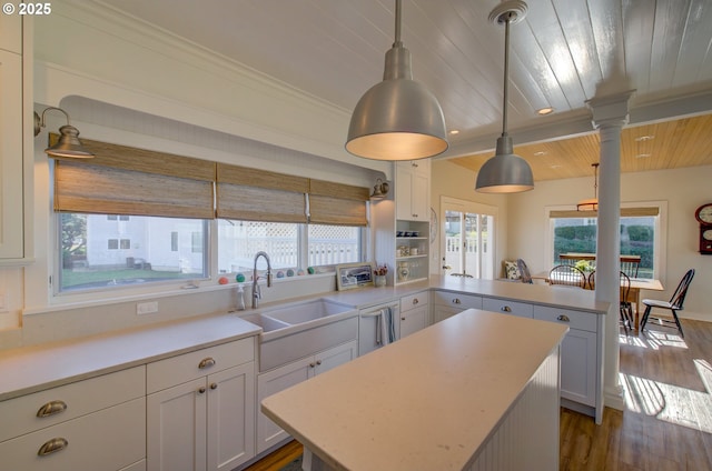 kitchen featuring white cabinetry, sink, kitchen peninsula, and decorative light fixtures