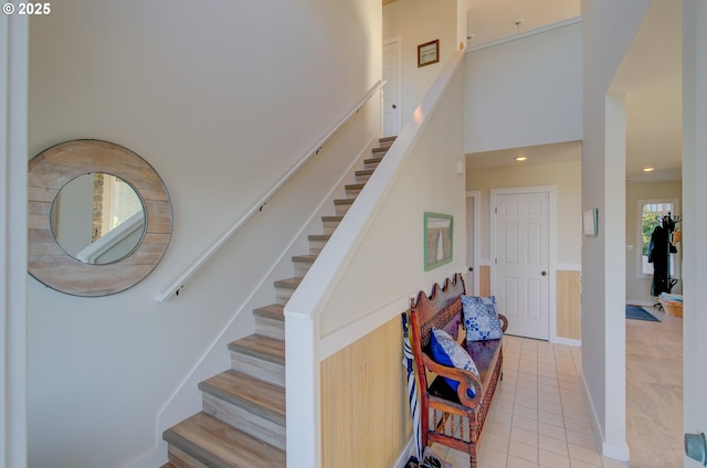 stairway featuring a towering ceiling and tile patterned flooring