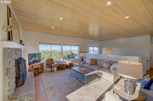 living room with a fireplace, light hardwood / wood-style flooring, and wooden ceiling