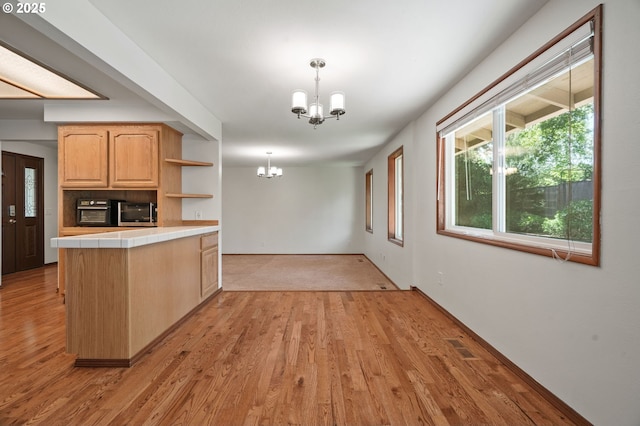 kitchen featuring tile counters, a chandelier, light wood-style flooring, and open shelves