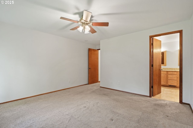 unfurnished bedroom featuring light carpet, baseboards, ensuite bath, and a ceiling fan