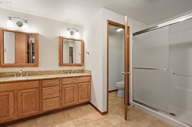 full bathroom featuring a shower stall, toilet, double vanity, and baseboards