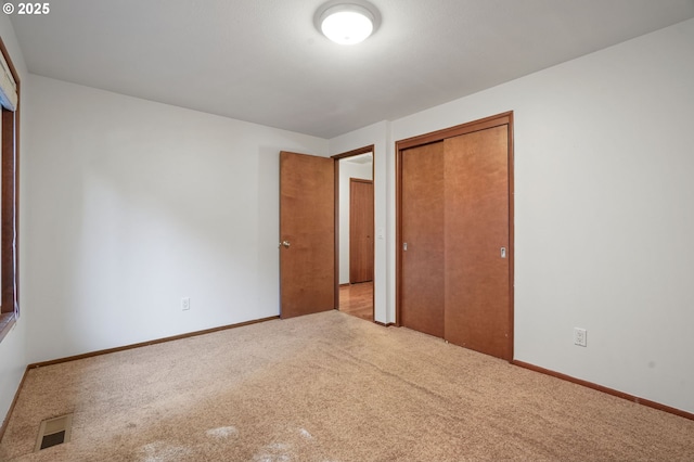 unfurnished bedroom with carpet flooring, a closet, and baseboards