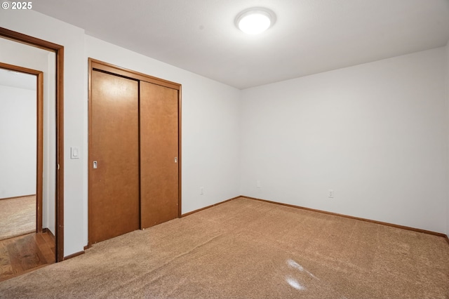 unfurnished bedroom featuring light carpet, a closet, and baseboards