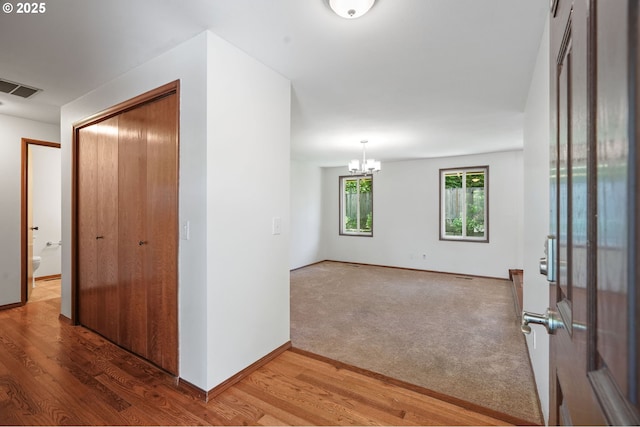 unfurnished room with wood finished floors, a chandelier, and baseboards