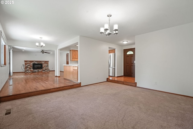 unfurnished living room featuring a chandelier, light colored carpet, and baseboards