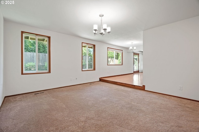 empty room with a chandelier, carpet, and baseboards