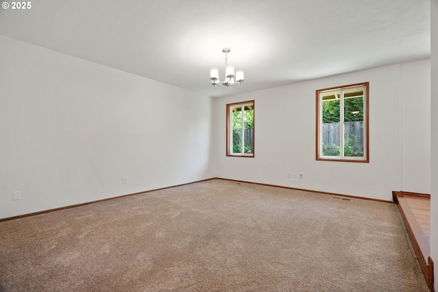 carpeted spare room featuring a chandelier and baseboards