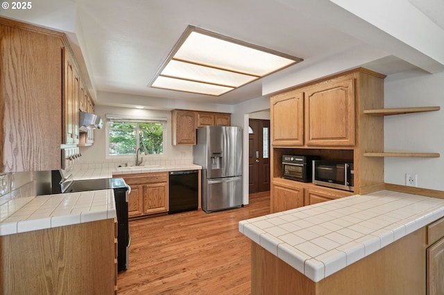 kitchen featuring stainless steel appliances, open shelves, wall chimney exhaust hood, light wood-style floors, and decorative backsplash