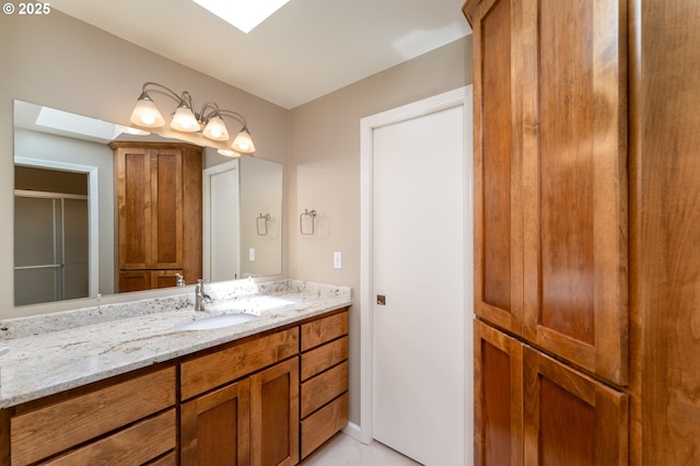 full bathroom with a skylight, vanity, a shower with door, and tile patterned floors