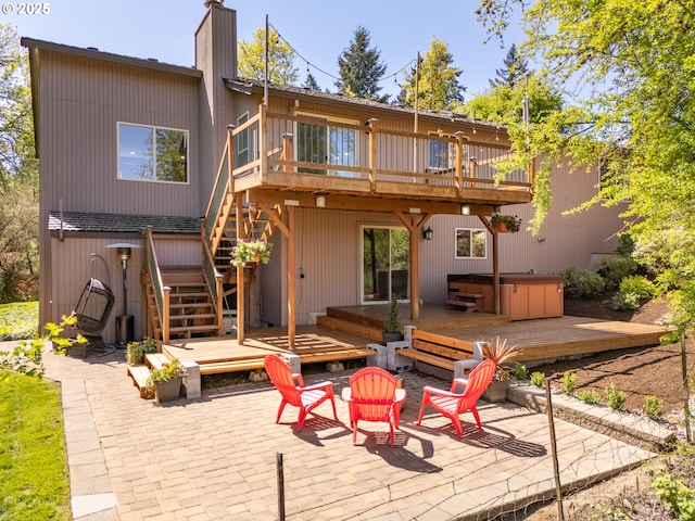 rear view of property with a hot tub, a patio area, and a wooden deck
