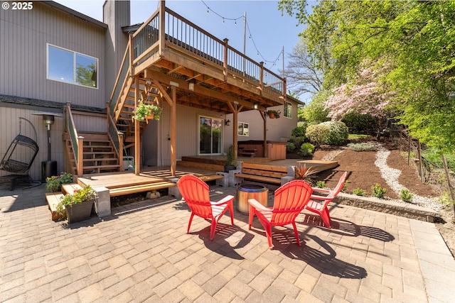 view of patio with a hot tub, a deck, a fire pit, and stairs