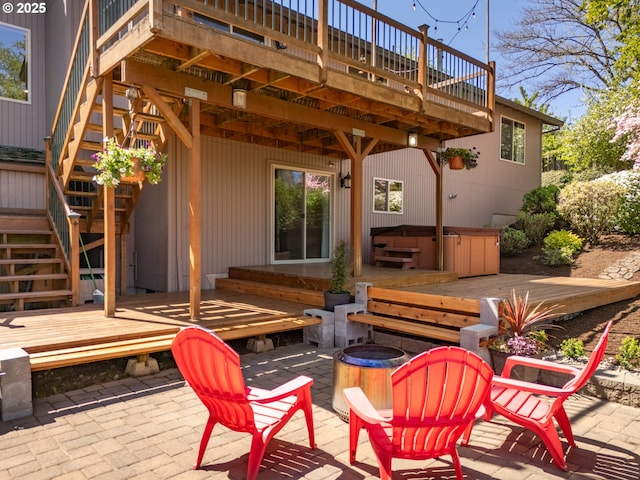 view of patio / terrace with stairs, a hot tub, a fire pit, and a deck